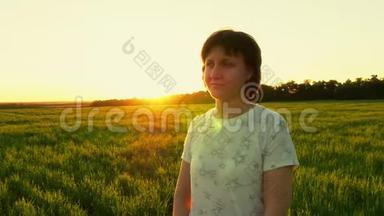 一个女孩站在绿色草坪上，在日落的背景下缓慢的动作
